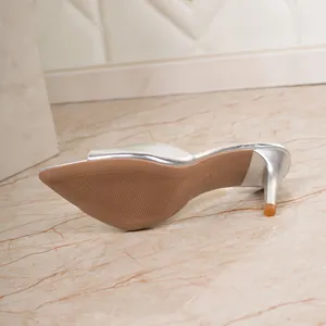Bottom view of silver high-heeled mule sandals showing sole texture and stiletto heel.