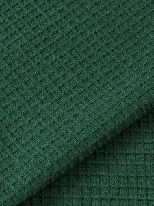 Detailed macro view of green waffle knit fabric texture for breathable men's Henley shirt