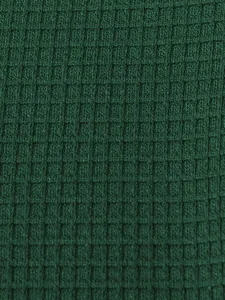 Macro view showing the green waffle knit fabric texture of this men's Henley shirt.
