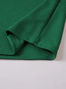 Detail view of green waffle knit fabric and hem stitching on a men's Henley shirt.