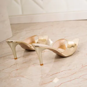 Close-up rear view of elegant golden metallic high-heeled mule sandals with thin stiletto heels.