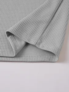 Close-up of the hem stitching and textured waffle-knit fabric of a grey Henley shirt.