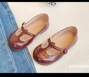 Detail view of brown T-strap Mary Jane leather shoes for girls on textured background