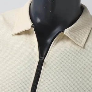 Gros plan sur la maille gaufrée et le zip noir de cette veste beige moderne pour hommes