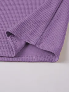 Close-up of the purple waffle knit fabric and stitched hem of a men's Henley T-shirt