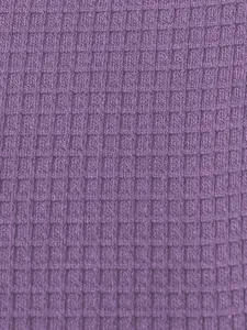 Macro view showing the detailed purple waffle knit fabric texture of a men's Henley shirt