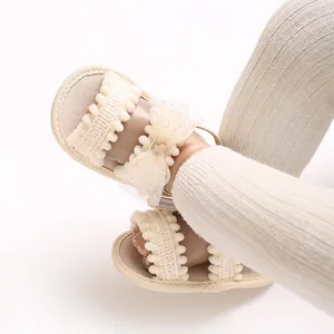 Vue rapprochée de sandales beige bébé avec nœud en dentelle et froufrous été