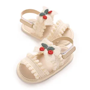Détail de sandales pour bébé avec cerises brodées et bordure décorative à pompons