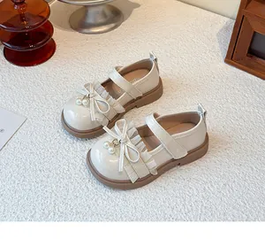 Nahaufnahme der beigen Mädchen-Mary-Janes mit eleganten Schleifen und Perlenanhängern