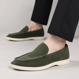 Gedetailleerde weergave van heren loafers in donkergroen suède aan de voeten van model