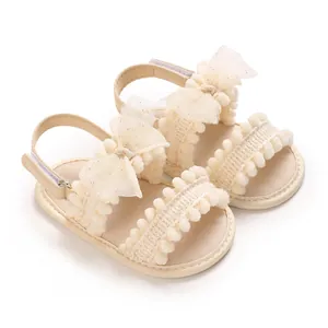 Vue détaillée de sandales beiges pour bébé fille avec nœuds en tulle et pompons