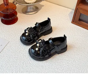 Detail von schwarzen Lacklederschuhen für Mädchen mit Rüschen und Perlenbogen