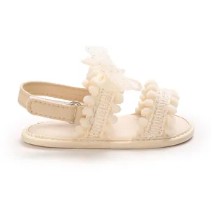 Détail d'une sandale beige pour bébé fille avec nœud décoratifs en dentelle