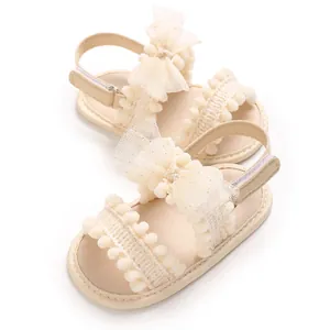 Vue détaillée de sandales beige pour bébé fille avec pompons en dentelle et nœuds