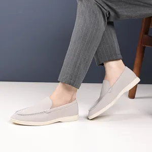 Detailed macro view of light grey slip-on loafers worn with stylish striped trousers.