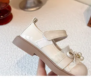 Nahaufnahme von cremeweißen Mädchen-Prinzessinnenschuhen mit schöner Perlen-Schleife und Spitze