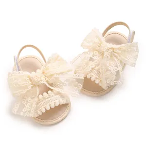 Vue détaillée de sandales crème pour bébé fille avec nœud en dentelle et pompons