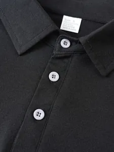 Detail view of black polo shirt collar with white buttons and fabric content tag
