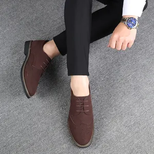 Top view of brown suede brogue shoes worn with black trousers and a luxury watch