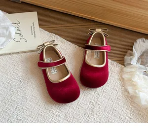 Dettaglio di scarpe da principessa per bambina in velluto rosso con eleganti fiocchi d'oro
