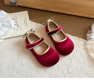 Dettaglio delle eleganti scarpe Mary Jane in velluto rosso per bambina con fiocco d'oro
