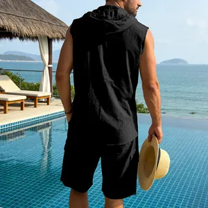 Back view of man in black linen sleeveless hooded shirt and cargo shorts by the pool