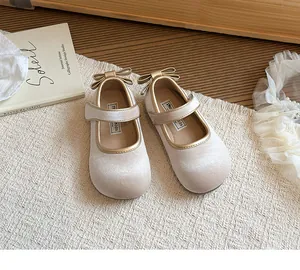 Dettaglio di scarpe Mary Jane in velluto champagne per bambine con fiocco dorato e cinturino