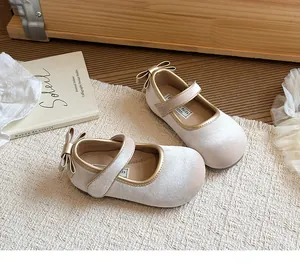Dettaglio delle scarpe da principessa per bambina con fiocco dorato e chiusura a strappo