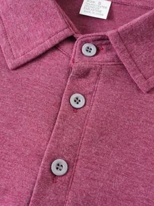Close-up detail of wine red polo shirt collar showing grey buttons and material tag