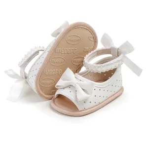 Vue détaillée de sandales blanches pour bébé avec nœud et perles à la cheville