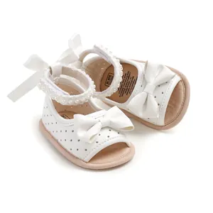 Vue macro détaillée de sandales blanches pour bébés avec nœud décoratif et perles