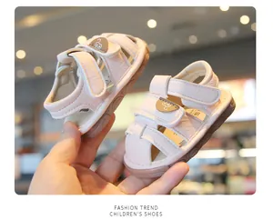 Close-up of pink soft-soled baby sandals with cute cartoon face and velcro straps
