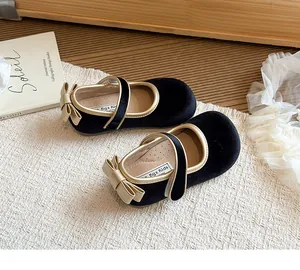 Dettaglio scarpe Mary Jane in velluto nero per bambina con fiocco dorato e cinturino.