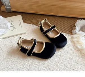 Dettaglio scarpe Mary Jane da bambina in velluto nero con rifiniture e fiocco oro