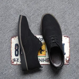 Top view of black suede Brogue shoes with wingtip perforations on grey carpet