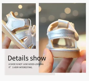 Detailed view of silver baby girl sandals with pearl bow accent and soft rubber sole