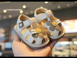 Close-up of cream baby sandals with daisy flower details and hollow-out design