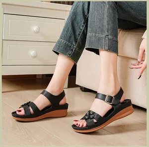 Close-up of black wedge sandals with flower detail and ankle strap buckle.