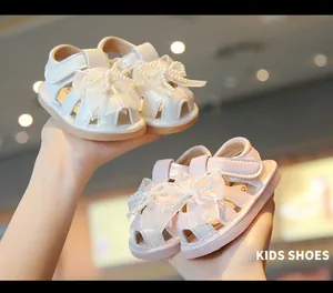 Close-up of delicate pearl bow details on toddler white and pink summer sandals