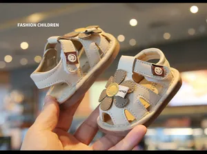 Close-up of cream baby girl sandals with flower detail and soft rubber sole