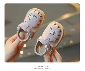 Detailopname van roze geborduurde bloemen kindersandalen met zachte antislipzool