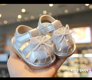 Detailed macro view of silver baby sandals featuring an elegant pearl-beaded bow