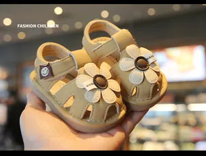 Close-up detail of beige baby sandals featuring cute white flower and soft leather texture