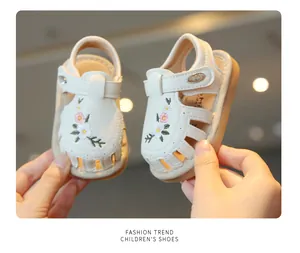 Gedetailleerd overzicht van wit geborduurde baby meisje sandalen met bloemmotief