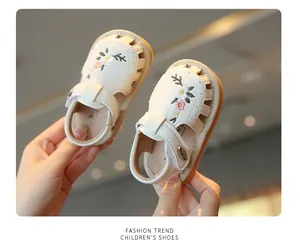 Detailopname van het bloemenborduurwerk op de witte sandalen voor peutermeisjes
