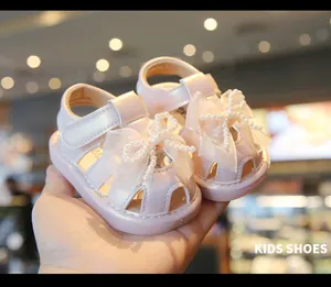 Detailed view of pink baby girl sandals featuring a delicate pearl bow and closed toe