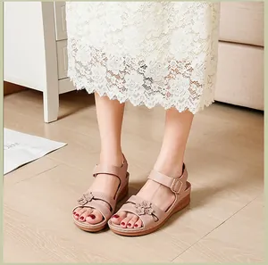 Close-up detail of women's pink wedge sandals with elegant floral accents on strap