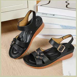 Detail of black wedge sandals featuring decorative floral accents and buckle strap.