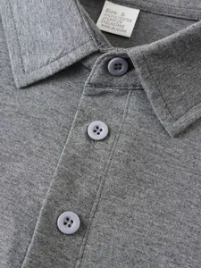 Detailed close-up of grey men's polo shirt collar and buttons with clear fabric texture