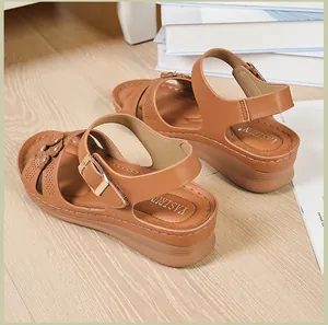 Detailed view of women's brown wedge sandals with floral patterns and buckle strap.